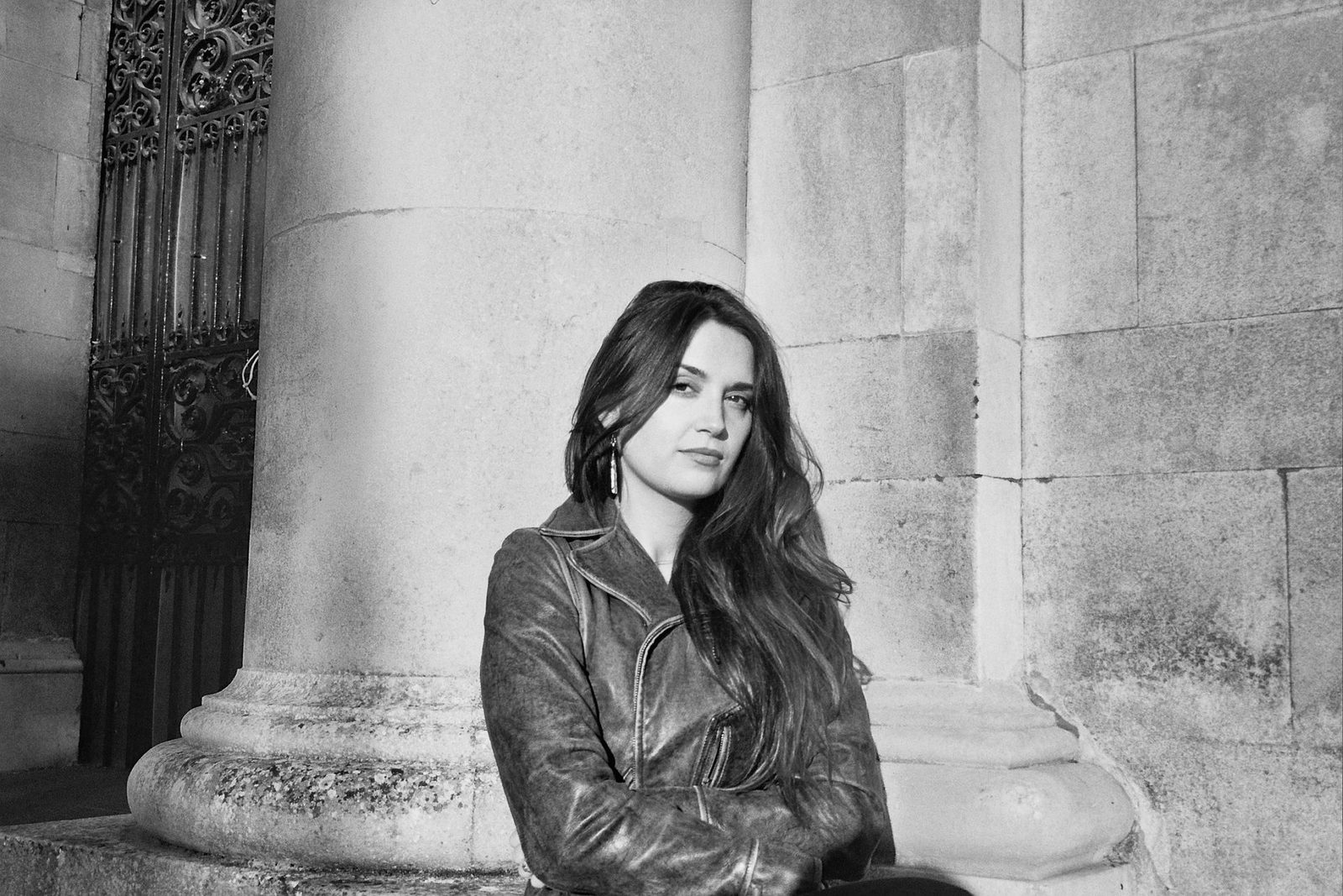 Alice Figes sitting at the base of a stone column. Black and white photograph.